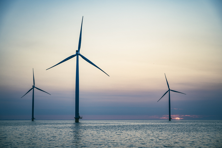 Wind Turbines In An Offshore Wind Park Producing Electricity During Sunset.
