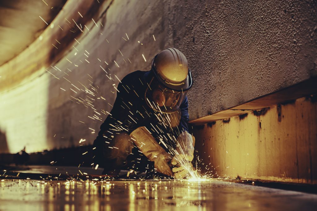 Male Worker Metal Cutting Spark On Tank Bottom Steel Plate With Flash Of Cutting Light Close Up Wear Protective Gloves And Mask