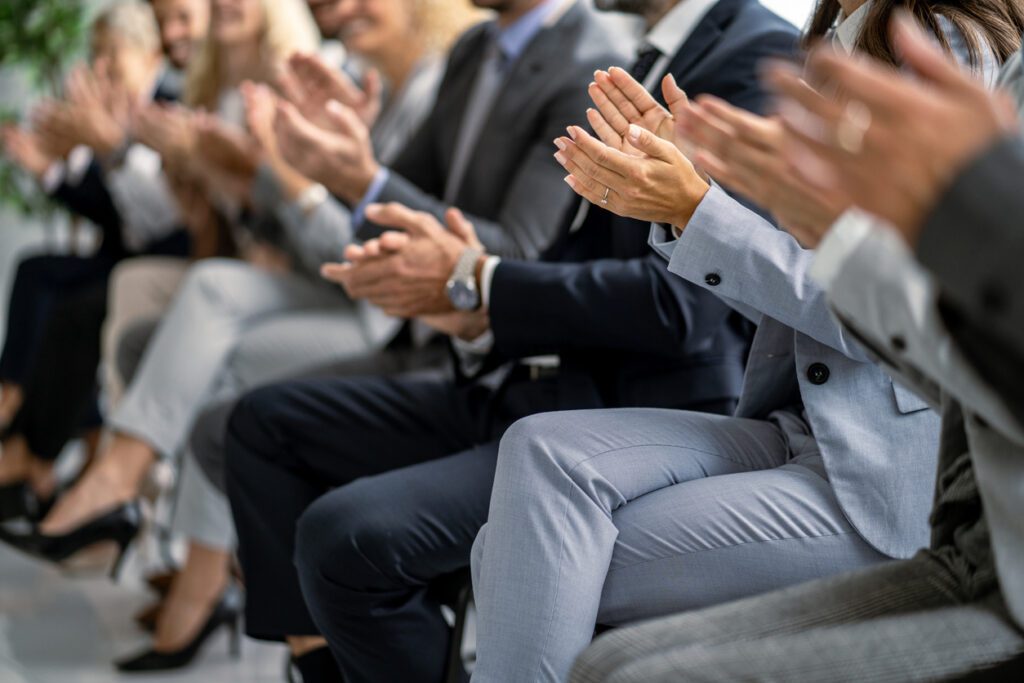 Audience Applauding Enthusiastically At Captivating Business Presentation.