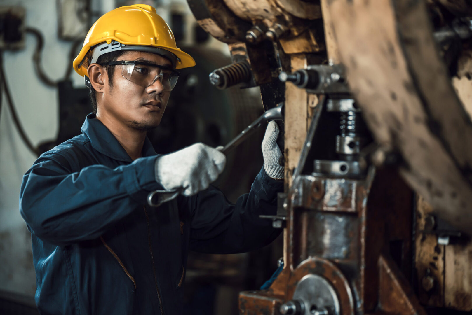 Asian Engineer Mechanic Man Checking And Using Wrench For Maintenance Pressing Metal Machine At Factory, Worker At Industrial Working Concept