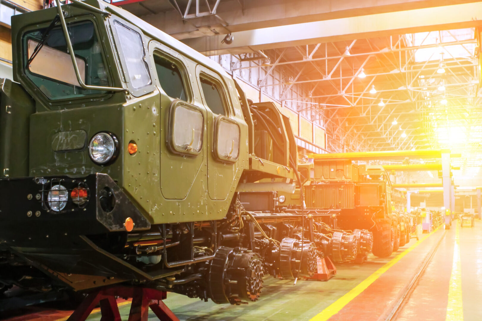 Military Vehicles In A Large Industrial Facility During Sunset, Showcasing Advanced Engineering And Design